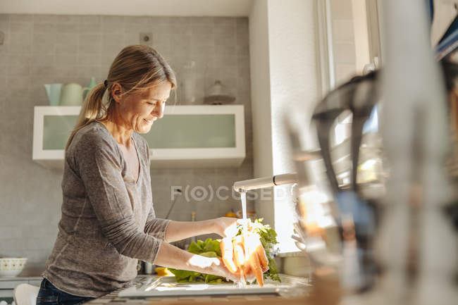Жінка в кухні миття морква — стокове фото