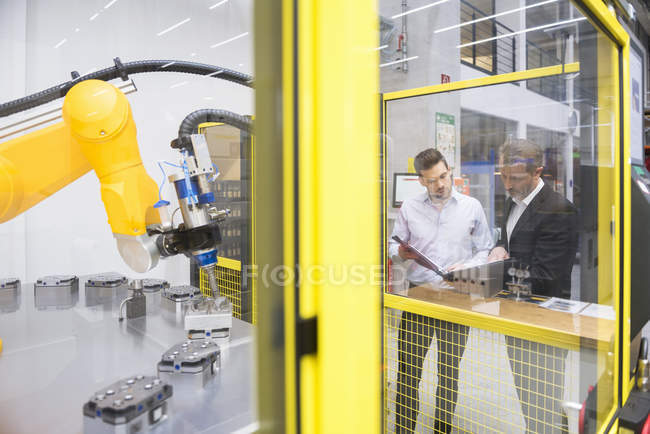 Imprenditori che osservano robot industriali — Foto stock
