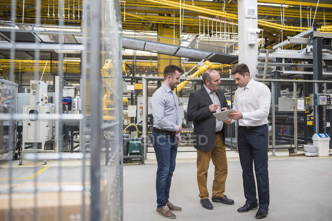 Männer mit Tablet reden in Fabrik — Stockfoto