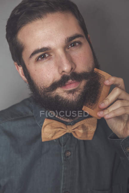 Man combing beard with wooden comb — Stock Photo