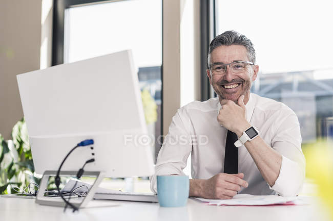 Businessman sitting at desk in office — Stock Photo