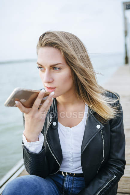 Frau am Telefon sitzt auf Promenade — Stockfoto