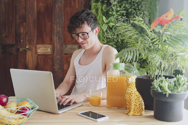 Man using laptop sitting at table — Stock Photo