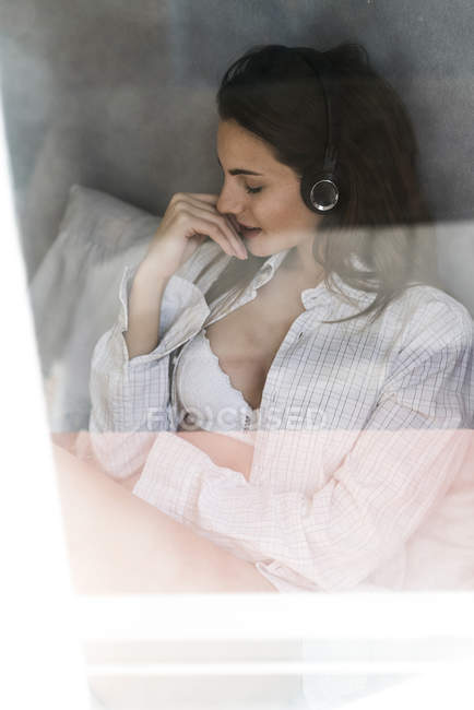Donna dietro il vetro della finestra ascoltare musica — Foto stock