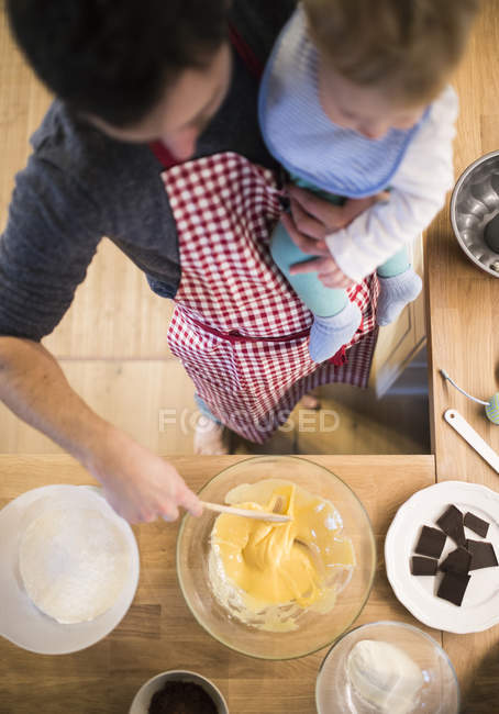 Отец и малыш пекут торт на кухне. — стоковое фото