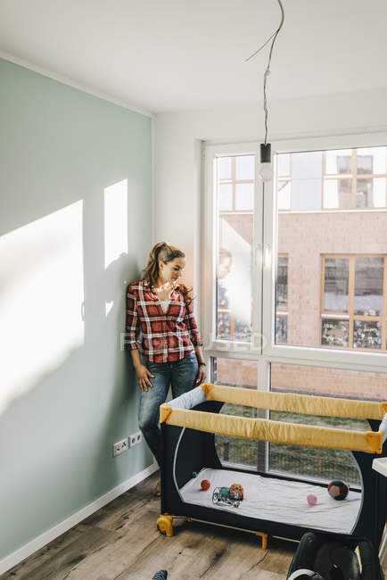 Femme mature regardant lit bébé dans une nouvelle maison — Photo de stock