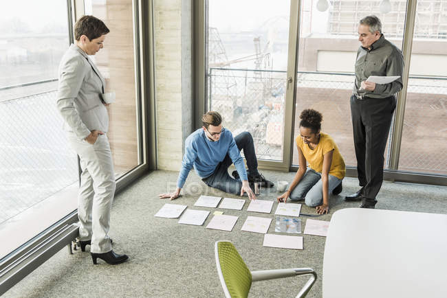 Porträt eines Geschäftsmannes, der Dokumente auf dem Fußboden sortiert — Stockfoto