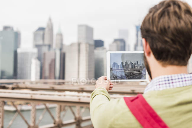 Usa, new york, brooklyn bridge, rückansicht eines mannes, der ein foto von citycsape macht — Stockfoto