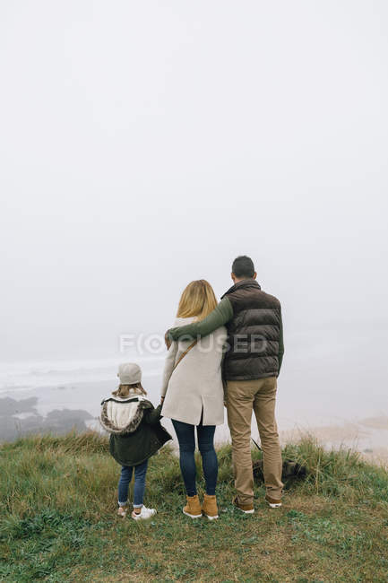 Spagna, Asturie, Vista posteriore di una famiglia irriconoscibile che guarda la spiaggia in una giornata nebbiosa — Foto stock