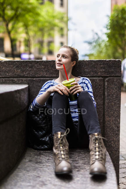 Retrato de mujer joven sentada con batido verde - foto de stock