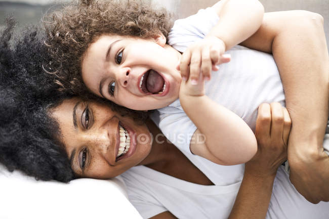 Mãe cócegas pequeno filho na cama — Fotografia de Stock