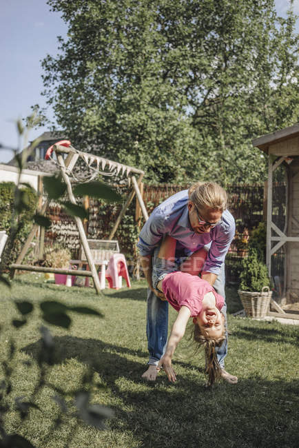 Father playing with happy daughter in garden — Stock Photo