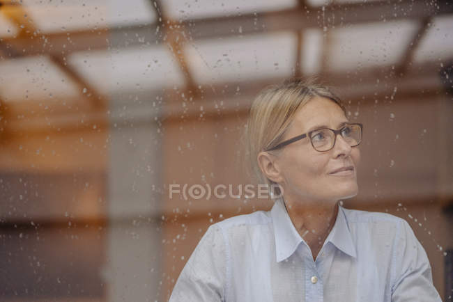 Businesswoman looking away behind windowpane — Stock Photo