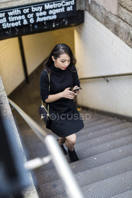 Portrait of young woman using smartphone on staircase — Stock Photo