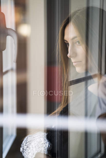 Жінка стоїть і дивиться через вікно — стокове фото