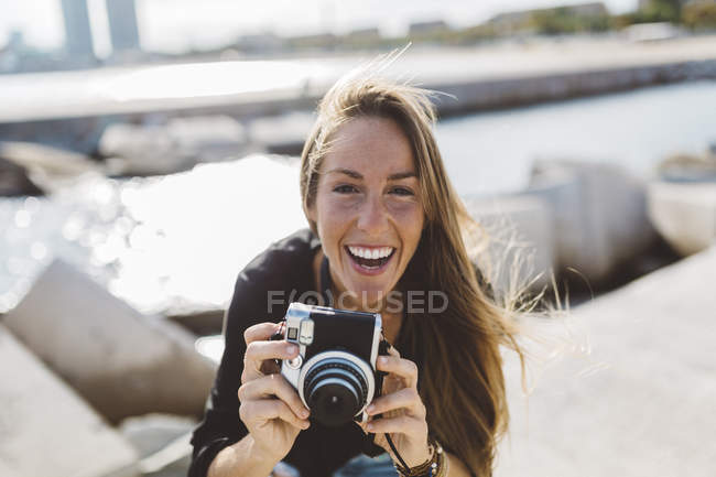 Portrait de jeune femme heureuse avec caméra à l'ancienne en bord de mer — Photo de stock