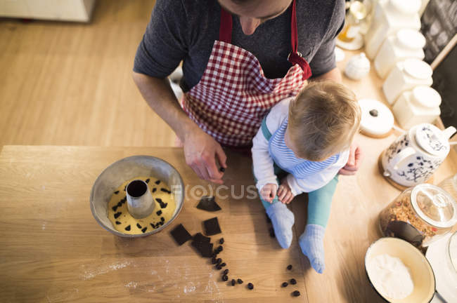 Отец и малыш на кухне пекут торт — стоковое фото