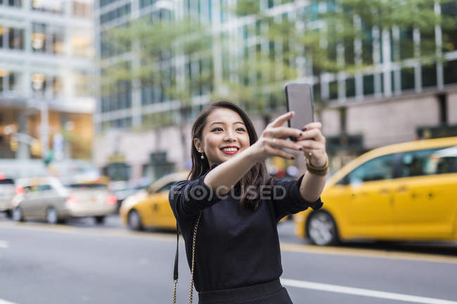 Ritratto di una giovane donna che fa selfie in strada — Foto stock
