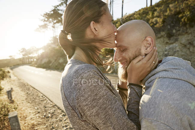 Jovem mulher beijando namorado na testa — Fotografia de Stock