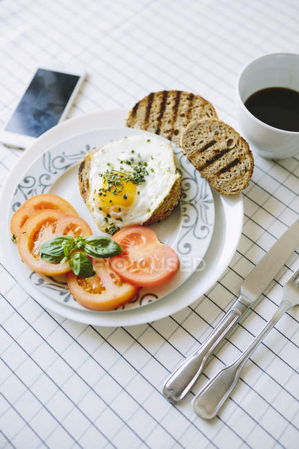 Closeup view of fried egg with tomato slices and toasts — Stock Photo