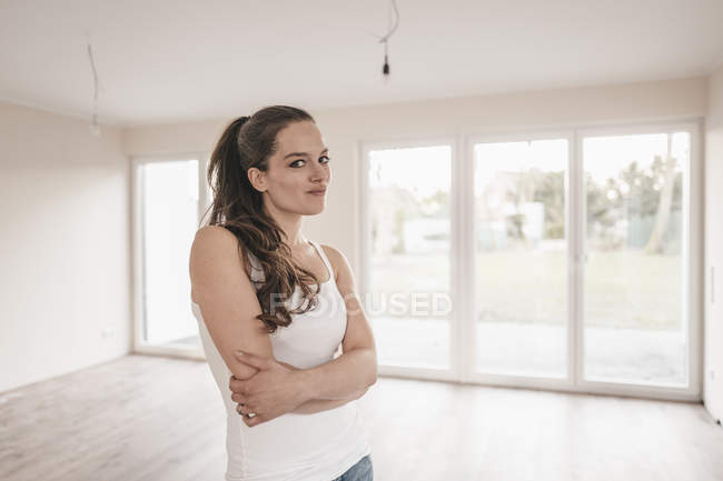 Donna in piedi in appartamento vuoto con le braccia incrociate — Foto stock