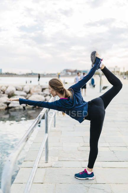 Jeune femme faisant des poses de yoga à la plage — Photo de stock