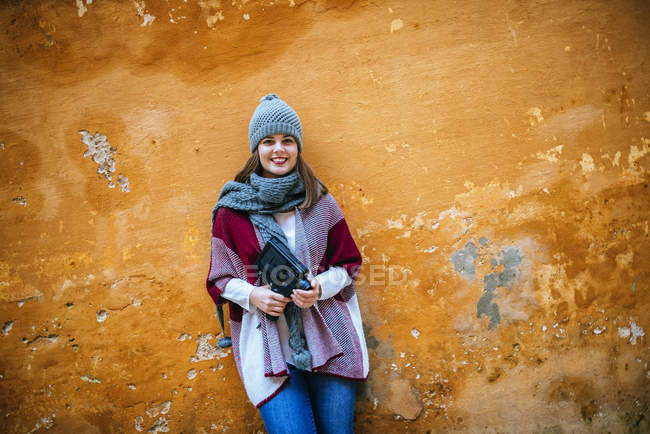Retrato de mujer joven con cámara delante de la pared naranja - foto de stock