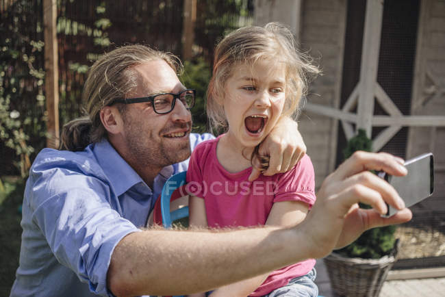 Father and daughter taking selfie in garden — Stock Photo