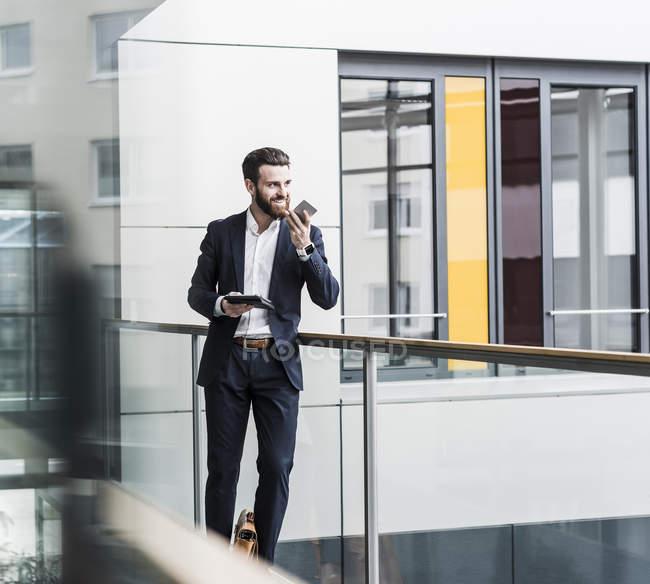 Porträt eines jungen Geschäftsmannes mit Smartphone und Tablet — Stockfoto