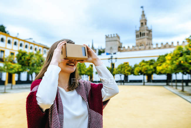 Donna che utilizza occhiali di realtà virtuale su cartone con Giralda sullo sfondo in Spagna, Andalusia, Siviglia — Foto stock