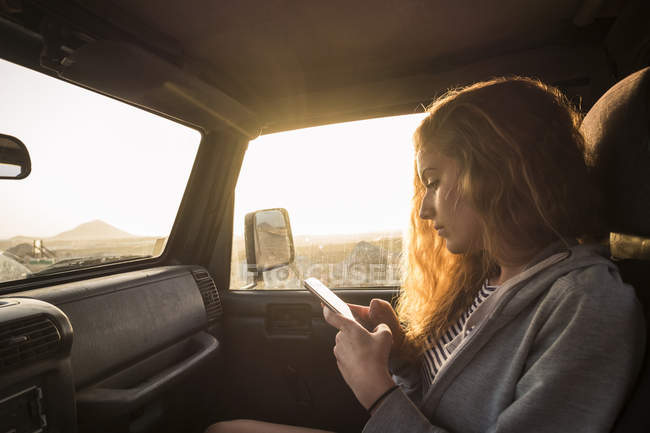 Jeune femme utilisant un téléphone cellulaire dans la voiture — Photo de stock