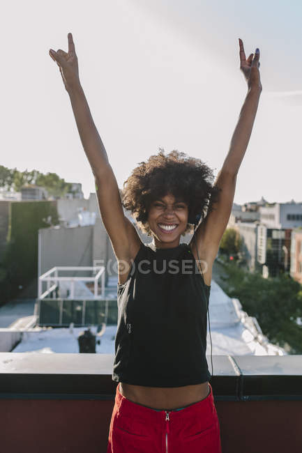 Retrato de mujer joven levantando las manos en la terraza de la azotea - foto de stock