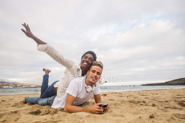 Attraente multiculturale giovane coppia sdraiata insieme sulla spiaggia — Foto stock