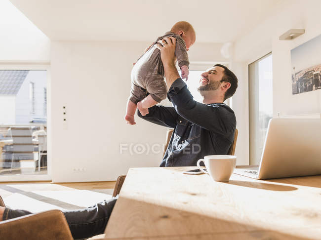 Father sitting at home and playing with baby son — Stock Photo
