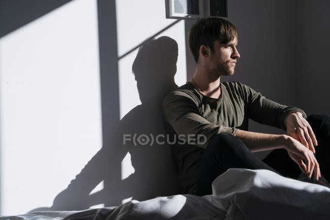 Uomo seduto sul letto a casa — Foto stock