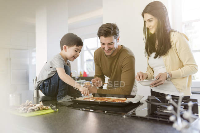 Familie bereitet gemeinsam Pizza in Küche zu — Stockfoto