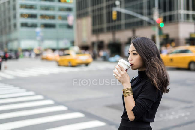 Portrait of young woman drinking at street — Stock Photo
