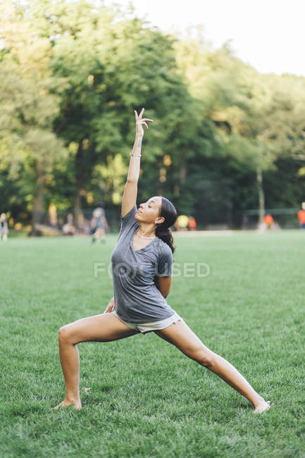 Jeune femme afro-américaine attrayante faisant des étirements au parc — Photo de stock