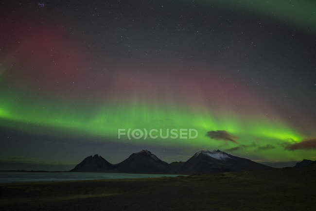 Scenic landscape with aurora borealis over the mountains shining at night, Iceland — Stock Photo