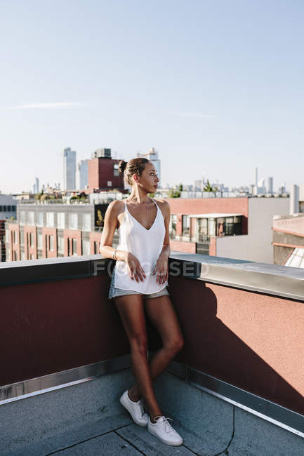 Retrato de mujer joven de pie en la terraza de la azotea - foto de stock