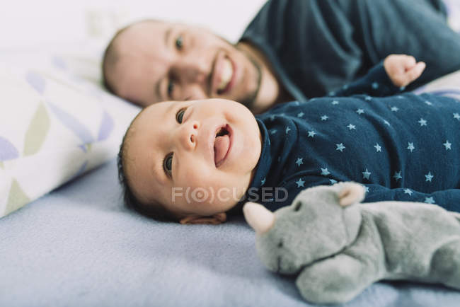 Счастливая новорожденная девочка лежит на кровати с отцом — стоковое фото