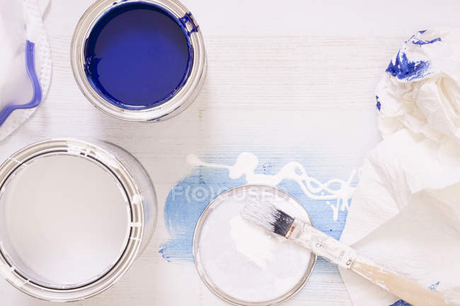 Pinceles y latas de pintura usados con barniz azul y blanco - foto de stock