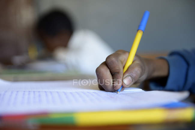 Close-up of Schoolboy writing in notebook in elementary school — Stock Photo
