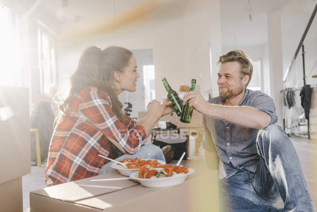 Couple eating salad and drinking beer in new home — Stock Photo