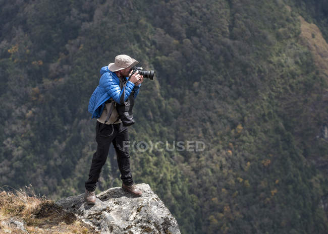 Männlicher Fotograf steht mit Kamera auf Felsen — Stockfoto