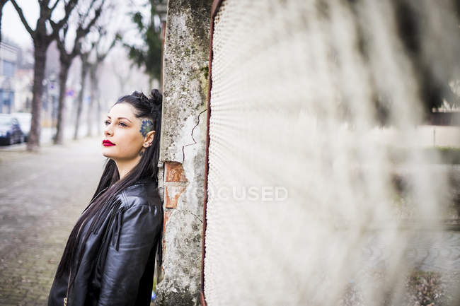 Jeune femme rêveuse appuyée contre le mur — Photo de stock