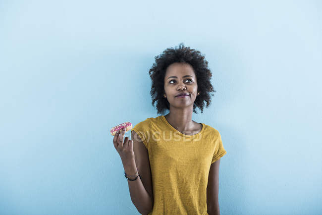 Портрет молодої жінки, що тримає пончик перед синій стіни — стокове фото
