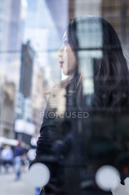 Retrato lateral da jovem mulher de pé perto de vidro painel — Fotografia de Stock
