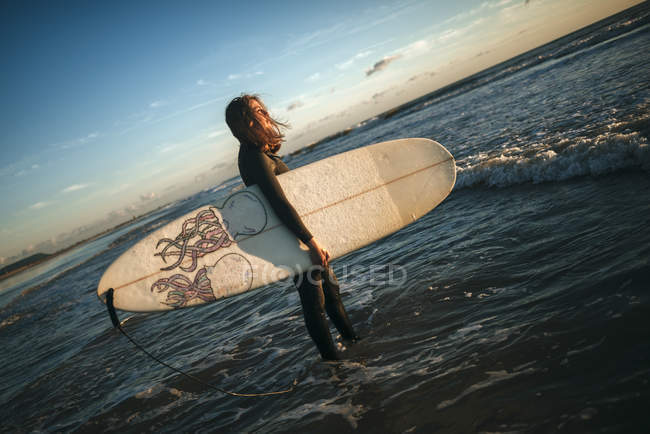 Spagna, Andalusia, Cadice, Conil de la Frontera, Surfista vestita in neoprene che entra in acqua con tavola da surf . — Foto stock