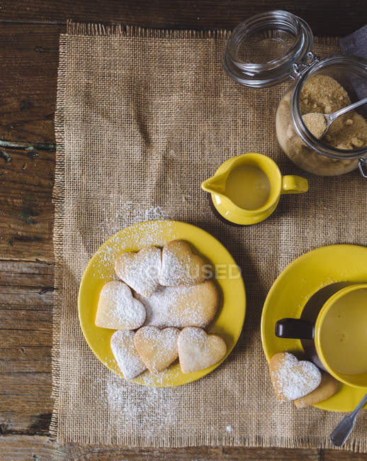 Домашнее печенье в форме сердца в тарелке с молоком и коричневым сахаром на дереве — стоковое фото